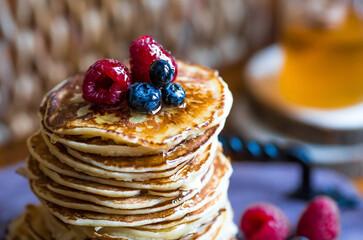 Delicious pancakes with honey, blueberries and raspberries. Russian traditions. The concept of the...