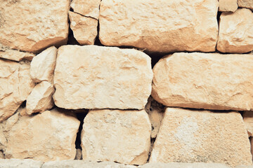 Ancient wall made of large stones. Old wall made of large and small natural stone.