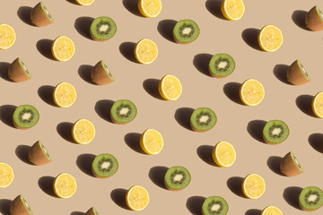 Crative pattern made with fresh lemons and kiwis against pastel beige background. Minimal summer fruit layout..