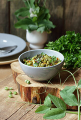 Vegan protein meal, dish of  stewed green legume vegetables: peas, green bean, broccoli garnished with parsley and flower petals, closep, overhead top down view, healthy vegan food concept