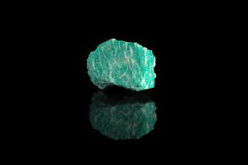Natural rock amazonite mineral stone from Kola Peninsula on black glass background.
