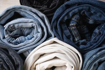 Jeans pants stack. Pile of jeans on light wooden background.