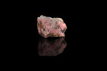 Natural mineral rock specimen - rough rhodonite stone from M. Sidelnikovo, Ural, Russia on black glass background.