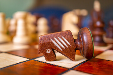 Fallen chess knight piece on a chessboard © Mirco Vacca/Wirestock