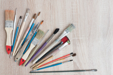 Obraz premium Top view of a table with a variety of artist brushes. There is room for text. Background, texture for a creative postcard