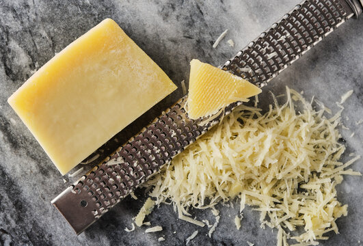 Grated Parmesan Cheese And Grater On Stone Table.