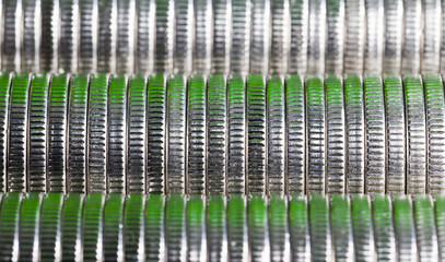 many round metal coins of silver color illuminated in green