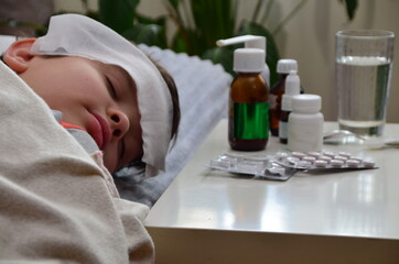 a boy with a cold is at home, being treated. there are medicines, medicine, throat and nose spray...
