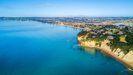 Aerial view of a beautiful suburb on the shore of a quiet harbour on a sunny morning. Auckland, New Zealand.