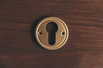Metal keyhole on a brown background. Top view. Copy, empty space for text