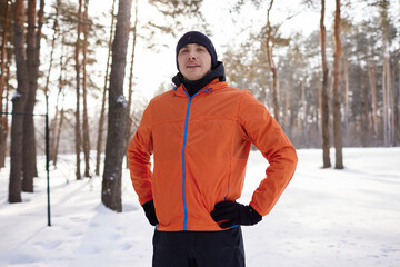 Fototapeta na wymiar A young man in bright sports clothes enjoys a jog in the woods on a winter day