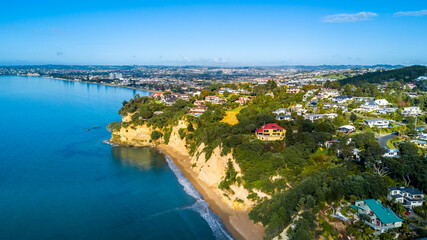 Aerial view of a beautiful suburb on the shore of a quiet harbour on a sunny morning. Auckland, New Zealand