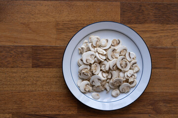 Fototapeta premium sliced ​​mushrooms on white plate and wooden background
