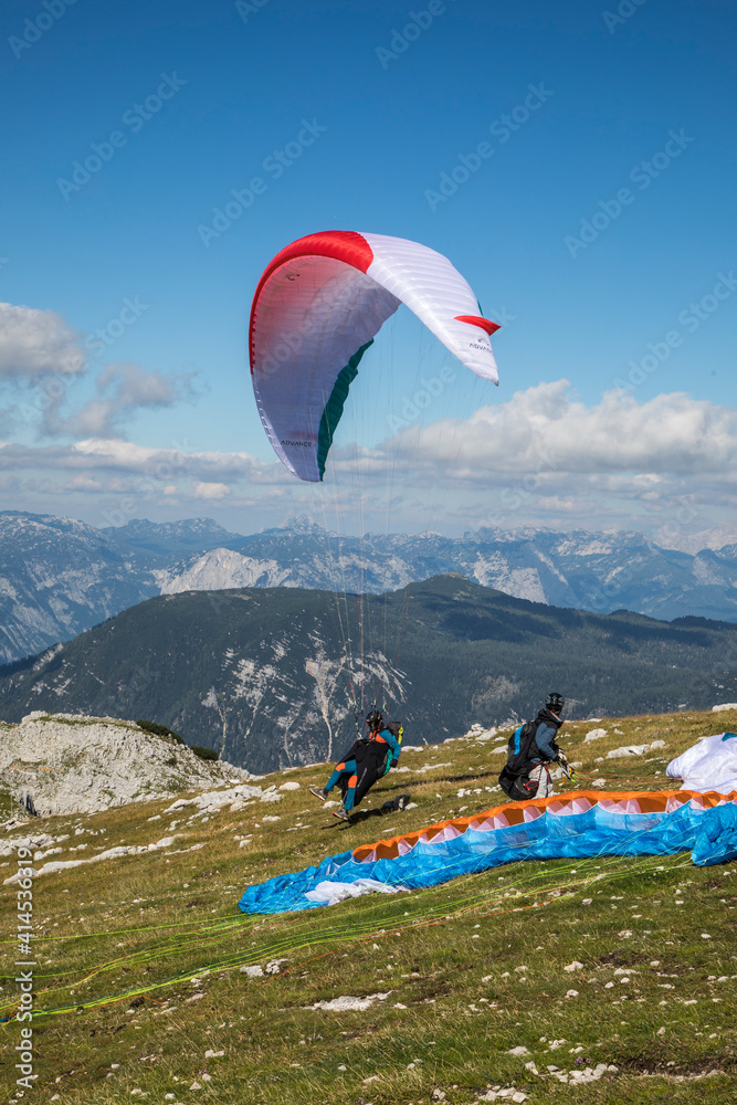 Poster  Austria, Dachstein, Paragliders preparing to take off above Lake Hallstatt and the surrounding mountains, all of which is part of the Salzkammergut Cultural Landscape, UNESCO World Heritage Site