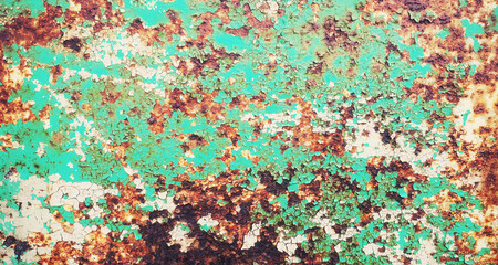 A textured metal surface, with rough rust destroying the outer layer. Colors: green, orange.
