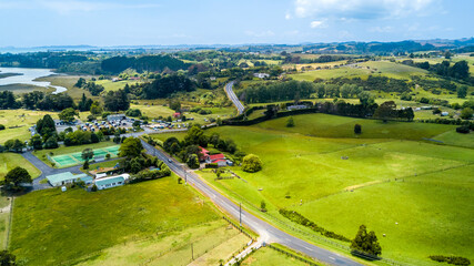 Aerial view on a highway running through countryside spotted with small farms and dwelling. Auckland, New Zealand.