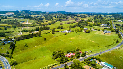 Obraz premium Aerial view on a highway running through countryside spotted with small farms and dwelling. Auckland, New Zealand.