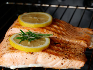 Close-up of ready-made salmon fillet with two lemons and rosemary, salmon in the oven. Healthy food concept