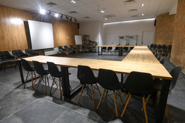  Interior of an empty U-shape conference hall with black chairs,  flipcharts and white screen.