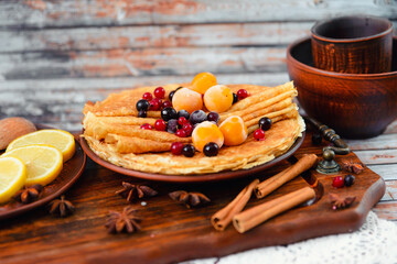 Golden pancakes with frozen fruits, decor and honey in a rustic style