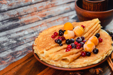 Golden pancakes with frozen fruits, decor and honey in a rustic style