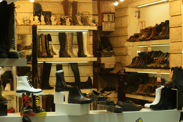 Variety of female boots on shelves at store. Showcase with womens footwear at shop.
