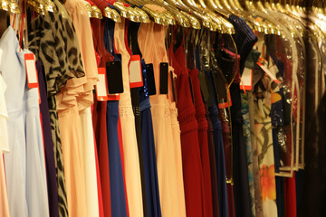 Rack of colorful evening dresses close up. Close up view of female clothing hanging on clothes rack. Fashion concept.