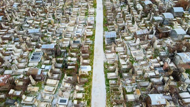 Aerial drone view of a cemetery in Chisinau, Moldova. Multiple graves, crypts, walkway, Cloudy weather, bare trees, winter