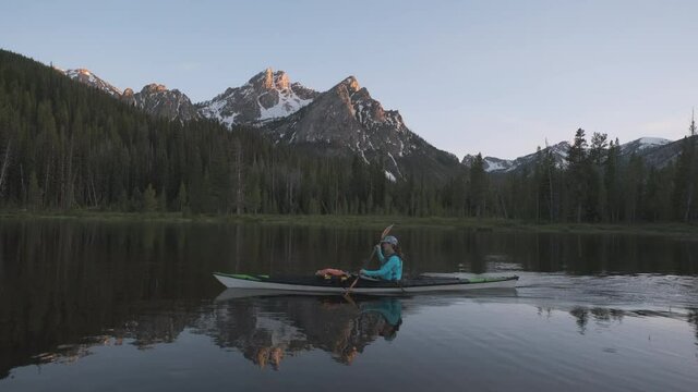 A woman kayaking on a mountain lake in Idaho.  