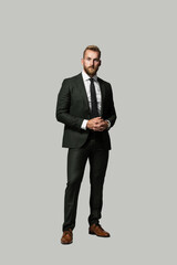 Serious looking handsome caucasian businessman looking serious with a beard and wearing a suit and tie, hands clasped on a grey background.