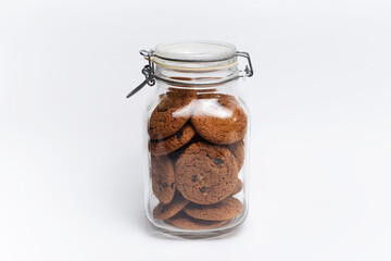 Close-up of oat cookies on glass jar on white background.