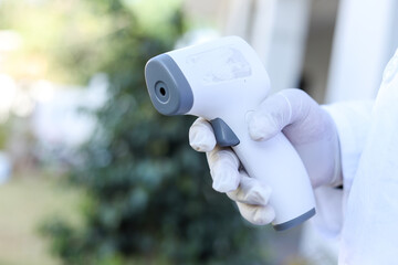 Shallow focus of a medical worker's hand holding a touchless thermometer