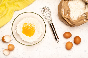 the process of making dough for pancakes with ingredients on a light table, eggs and flour are whipped with a mixer