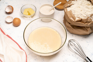 the process of making dough for pancakes with ingredients on a light table, eggs and flour are whipped with a mixer
