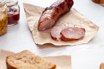 Sliced smoked sausage in a wooden table with bread and ketchup.