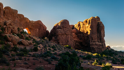 Wide shot of sunset light goes through red sandstone arch in arches national park in Utah, America