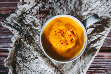 Soupe de courge et carottes aux baies roses dans un bol sur une table de cuisine en bois