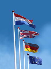 Flags of France, United Kingdom, Germany and European Union on flagpoles. Flag of France is on top.  Blue sky background.