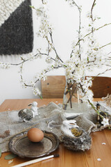 Fototapeta na wymiar Happy Easter! Natural Easter eggs, bunnies, feathers, nest and cherry petals on rustic linen