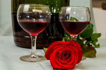 two glasses and a large bottle of wine and a rose