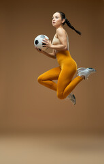 Sporty young woman with soccer ball jumping on the air