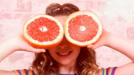 large portrait with a large grapefruit cut open, an orange covering the eyes