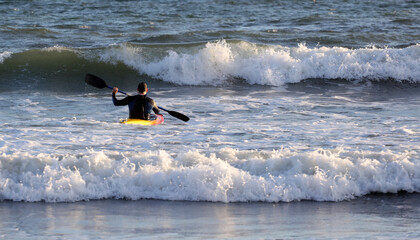 athlete with canoe, among the waves of the sea