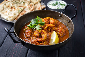 Traditional Indian jhinga masala with king browns served with chapati bread and raita as close-up...