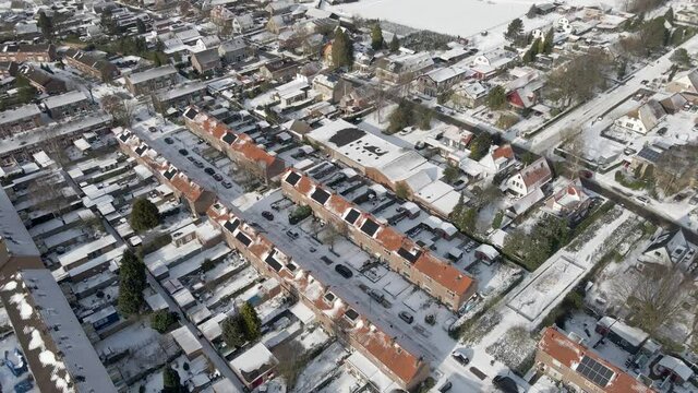 Aerial of suburban neighborhood covered in snow with solarpanels on rooftops of houses