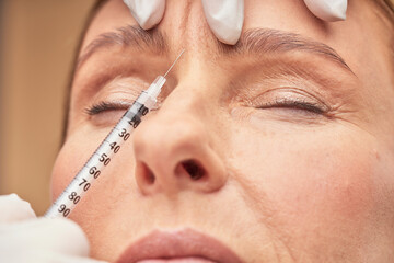 Anti Aging procedures. Close up shot of beautician in protective gloves making cosmetic injection in female forehead
