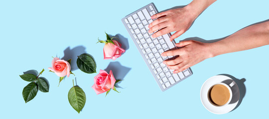 Woman using computer keyboard with pink roses - flat lay