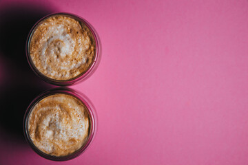 Top view of two latte art coffee in the form of figure eight, isolated on pink background.