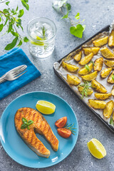Grilled salmon steak with basil and spices and baked potatoes served with gin and tonic on light...