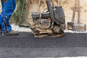 Construction Workers At Sidewalk Asphalting With Vibrator